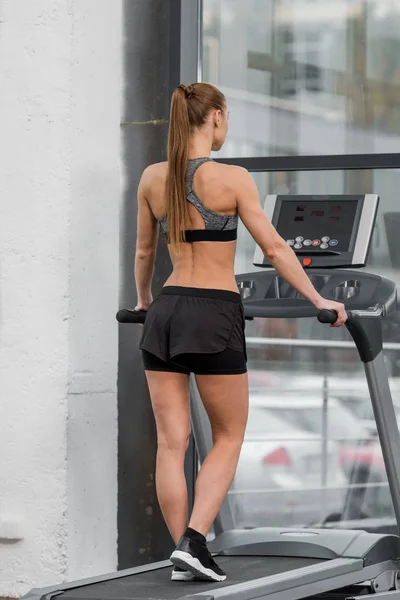 Back view of athletic sportswoman exercising on treadmill in gym — Stock Photo