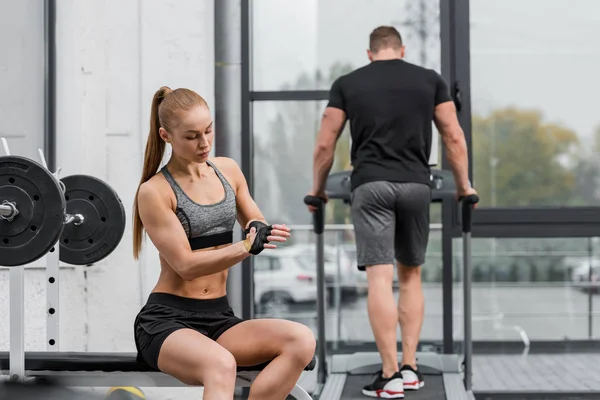 Allenamento sportivo su tapis roulant, sportiva con i guanti per allenarsi in palestra — Foto stock