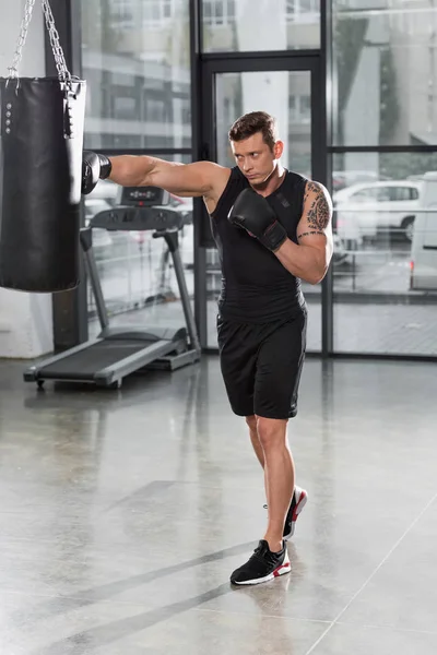 Entraînement de boxeur musclé beau avec sac de boxe dans la salle de gym — Photo de stock