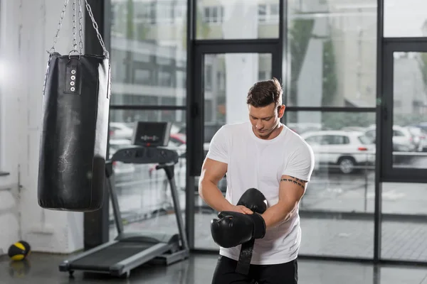 Handsome muscular boxer wearing boxing gloves in gym — Stock Photo