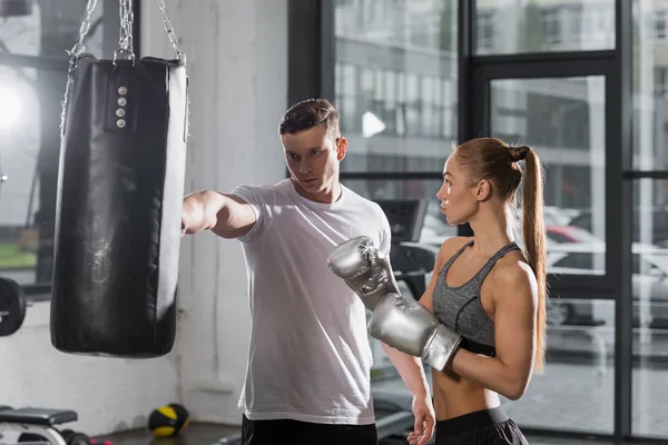 Entrenador guapo mostrando cómo boxear en el gimnasio - foto de stock