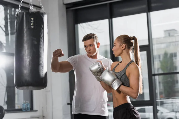 Entrenador guapo que muestra cómo boxear a la deportista en el gimnasio - foto de stock
