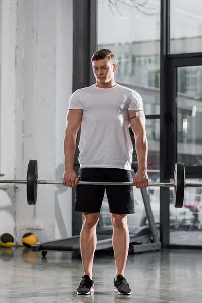 Entraînement de bodybuilder athlétique beau avec haltère dans la salle de gym — Photo de stock