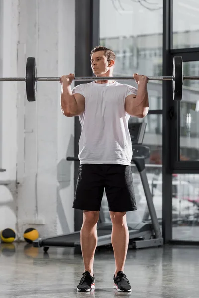 Treinamento musculoso bonito fisiculturista com barra no ginásio — Fotografia de Stock