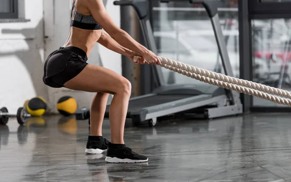 Imagen recortada de culturista atlético haciendo ejercicio con cuerdas en el gimnasio - foto de stock