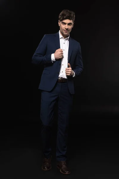 Full length portrait of handsome young businessman in stylish suit looking at camera isolated on black — Stock Photo