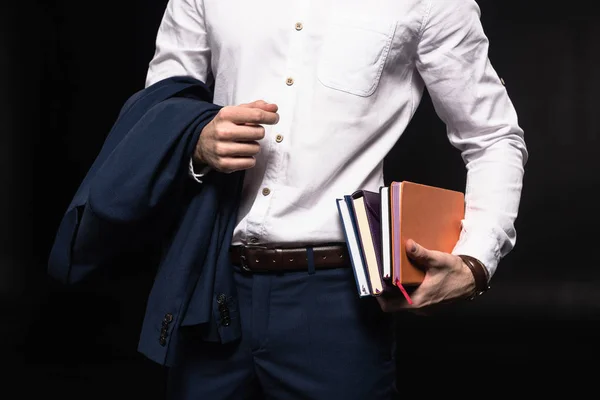 Abgeschnittene Aufnahme eines Geschäftsmannes mit einem Stapel von Notizbüchern, isoliert auf schwarz — Stockfoto