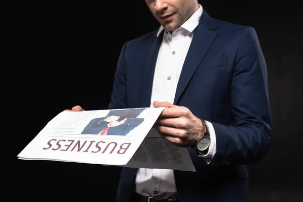 Cropped shot of young businessman reading newspaper isolated on black — Stock Photo