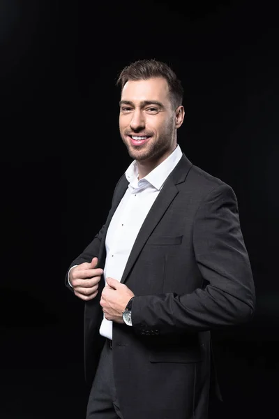 Handsome young businessman looking at camera isolated on black — Stock Photo