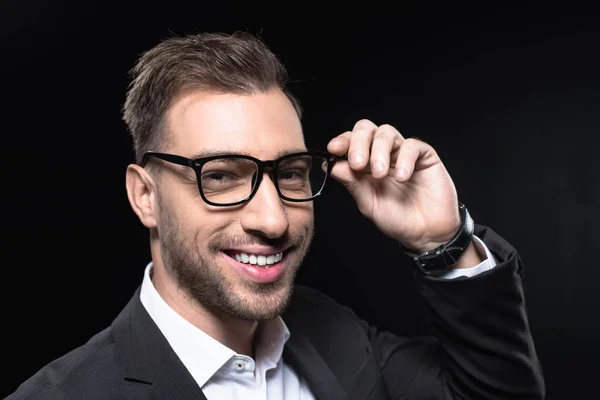 Close-up retrato de belo jovem empresário em óculos olhando para câmera isolada em preto — Fotografia de Stock