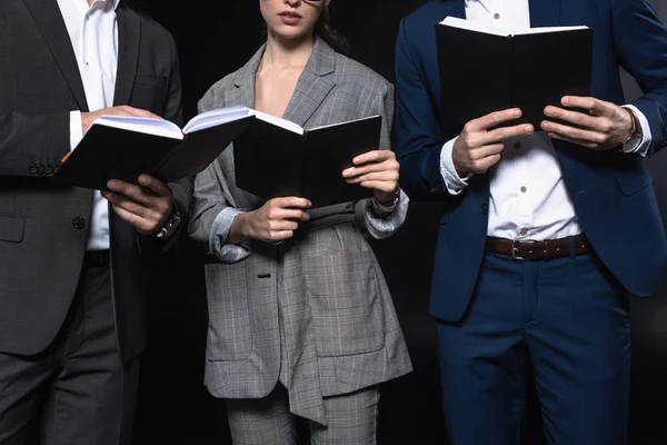Abgeschnittene Aufnahme einer Gruppe von Geschäftsleuten, die mit Notizbüchern zusammen arbeiten, isoliert auf schwarz — Stockfoto