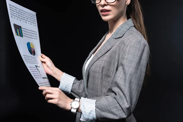 Plan recadré de jeune femme d'affaires dans une veste élégante tenant journal isolé sur noir — Photo de stock