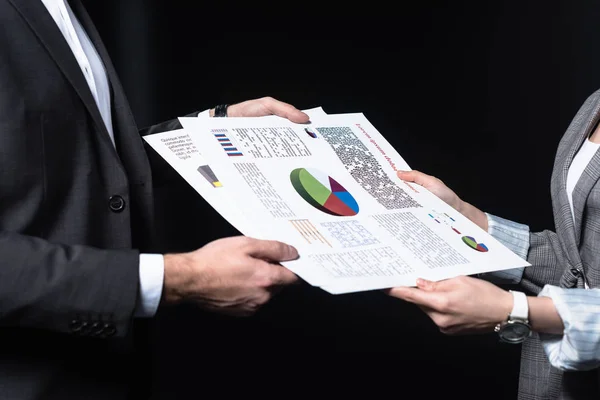 Обрезанный снимок бизнесменов, передающих документы с графиками, изолированными на черном — стоковое фото
