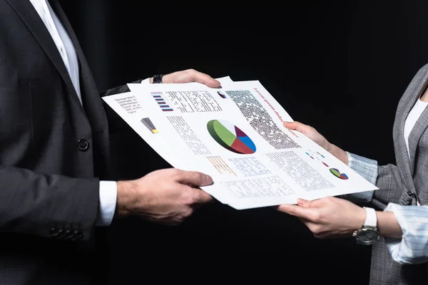 Cropped shot of business people passing documents with graphs isolated on black — Stock Photo