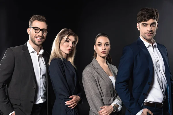 Group of business people looking at camera together while standing in row isolated on black — Stock Photo