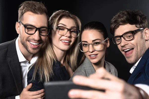 Close-up shot of group of happy business people taking selfie together isolated on black — Stock Photo
