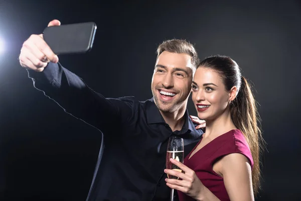 Heureux jeune couple prendre selfie avec smartphone pendant la fête sur noir — Photo de stock