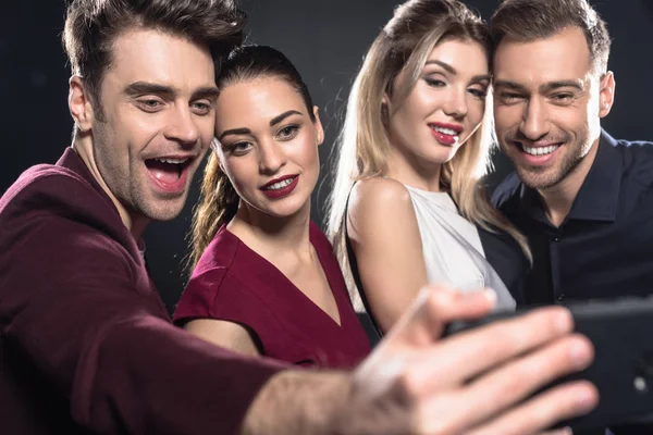 Close-up shot of group of friends taking selfie with smartphone during party on black — Stock Photo