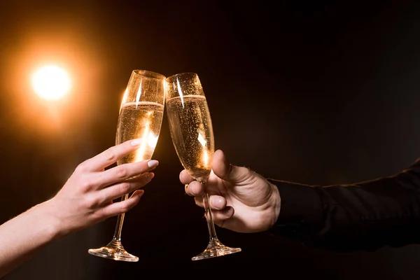 Cropped shot of couple clinking glasses of champagne under golden light — Stock Photo
