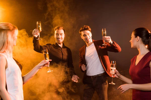 Grupo de amigos sonrientes brindando con champán durante la fiesta - foto de stock