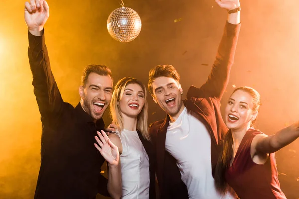 Grupo de amigos olhando para a câmera e celebrando durante a festa de férias — Fotografia de Stock