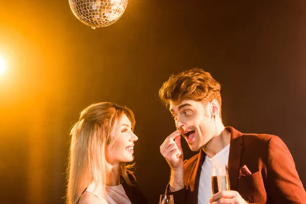 Close-up shot of happy flirting couple with champagne having fun during party under golden light — Stock Photo