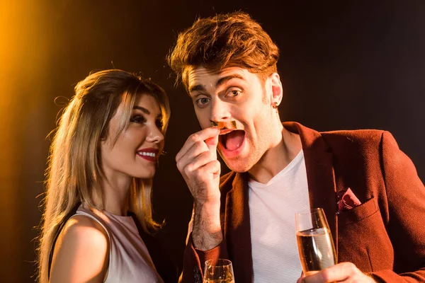 Primer plano disparo de feliz pareja joven con champán divertirse durante la fiesta bajo la luz dorada - foto de stock
