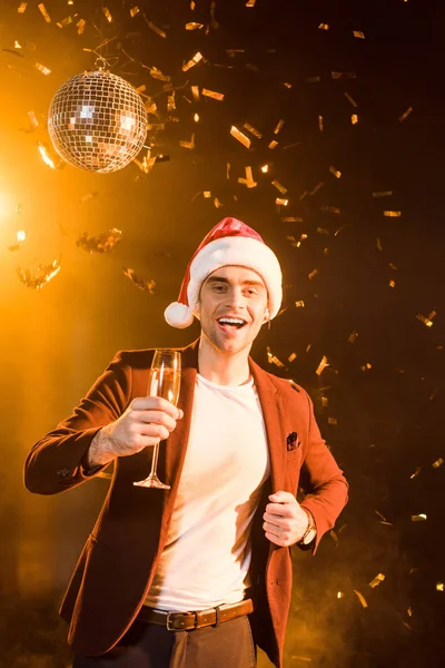 Jovem feliz com champanhe celebrando o Natal com confete caindo — Fotografia de Stock