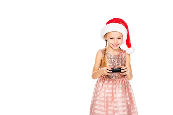 Adorable little child in santa hat playing video game and looking at camera isolated on white — Stock Photo