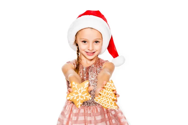 Adorable little child in santa hat with ginger cookies looking at camera isolated on white — Stock Photo