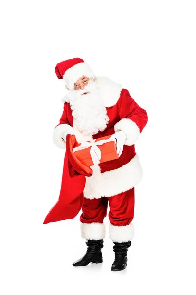 Santa claus putting present into bag isolated on white — Stock Photo