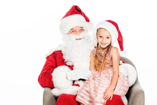 Happy santa claus and little child sitting in armchair together and looking at camera isolated on white — Stock Photo