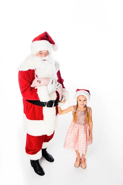 Hochwinkelaufnahme des Weihnachtsmannes mit Schwein und niedlichem lächelndem Kind, das isoliert auf weiß in die Kamera schaut — Stockfoto