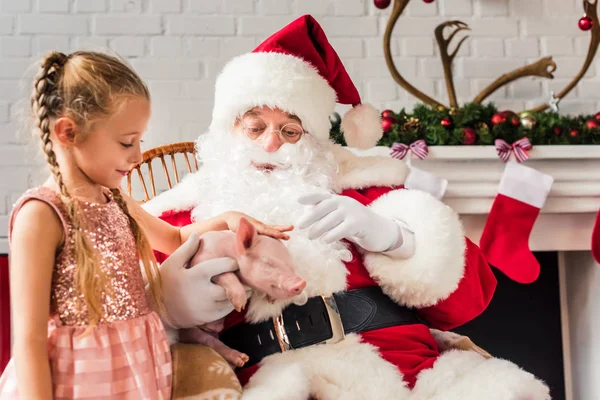 Santa claus and cute little child playing with piglet — Stock Photo