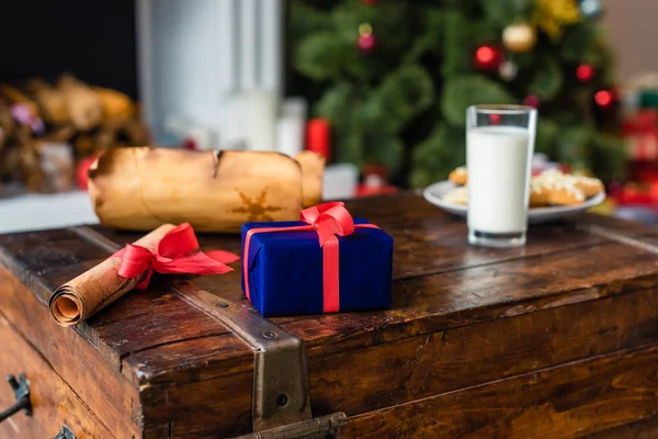 Close-up view of parchment, gift box and glass of milk with cookies on chest — Stock Photo