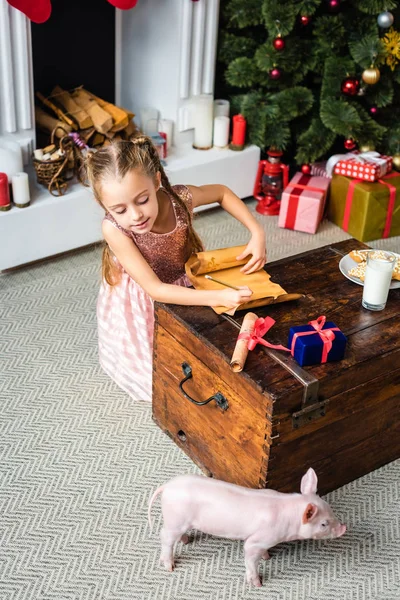 High angle view of cute little child writing wishlist and looking at piglet at christmas time — Stock Photo