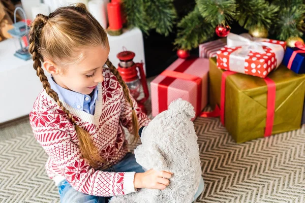 Adorable happy child playing with teddy bear at christmas eve — Stock Photo