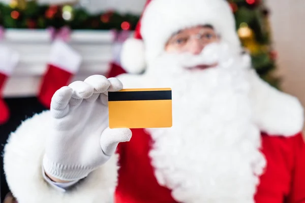 Vue rapprochée de Santa Claus tenant une carte de crédit et regardant la caméra, mise au point sélective — Photo de stock