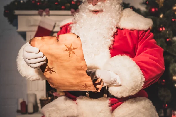 Cropped shot of santa claus holding parchment with wishlist — Stock Photo