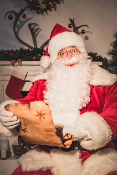 Удивленный Санта держит пергамент со списком желаний и смотрит в камеру — стоковое фото