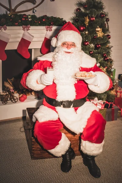 Santa claus holding plate with cookies and glass of milk — Stock Photo