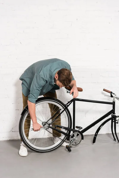 Joven hombre reparación de bicicleta por llave ajustable - foto de stock