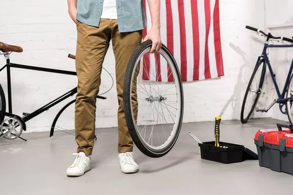 Cropped image of man holding bicycle wheel in hand — Stock Photo