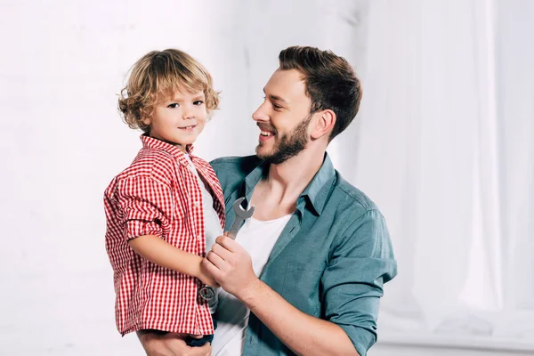 Portrait of happy father holding little son with spanner in hand — Stock Photo