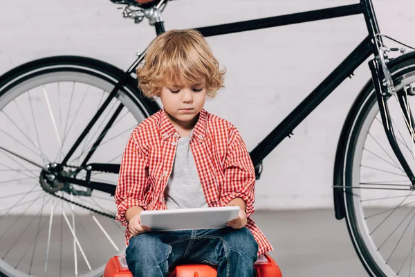 Selektiver Fokus des kleinen Jungen, der auf Werkzeugkiste sitzt und digitales Tablet benutzt — Stockfoto