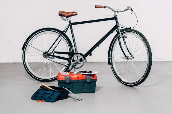 Селективный фокус велосипеда возле ящиков с инструментами с цифровым планшетом в мастерской — стоковое фото