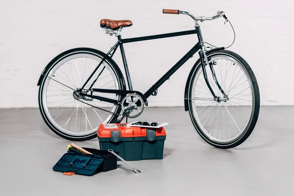 Selective focus of bicycle near tools boxes with digital tablet in workshop — Stock Photo