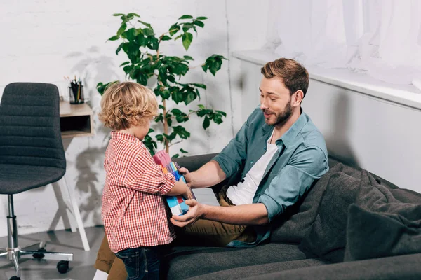 Bambino portando blocchi di plastica colorati al padre felice a casa — Foto stock