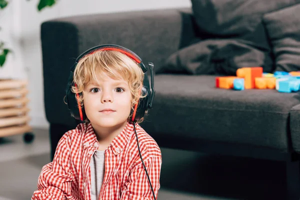 Primer plano retrato de niño pequeño escuchando música en los auriculares y mirando a la cámara - foto de stock