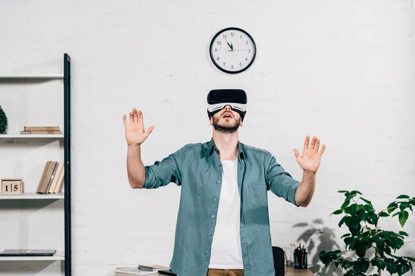 Messa a fuoco selettiva del giovane con braccia larghe utilizzando cuffie realtà virtuale a casa — Foto stock